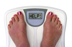 Girl's feet on weighing scale saying HELP